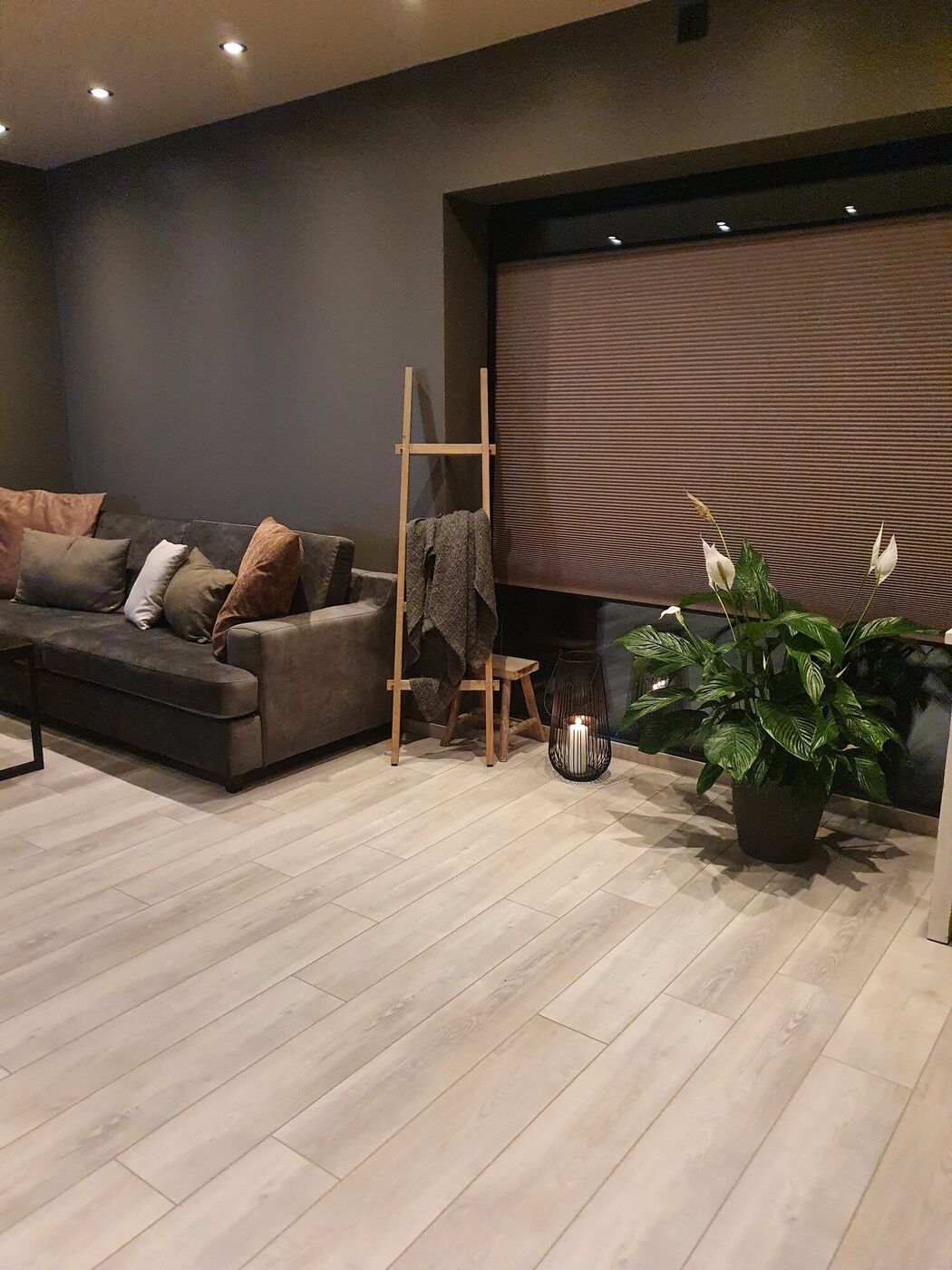 Lys stue med sofa, varmt tregulv og planter